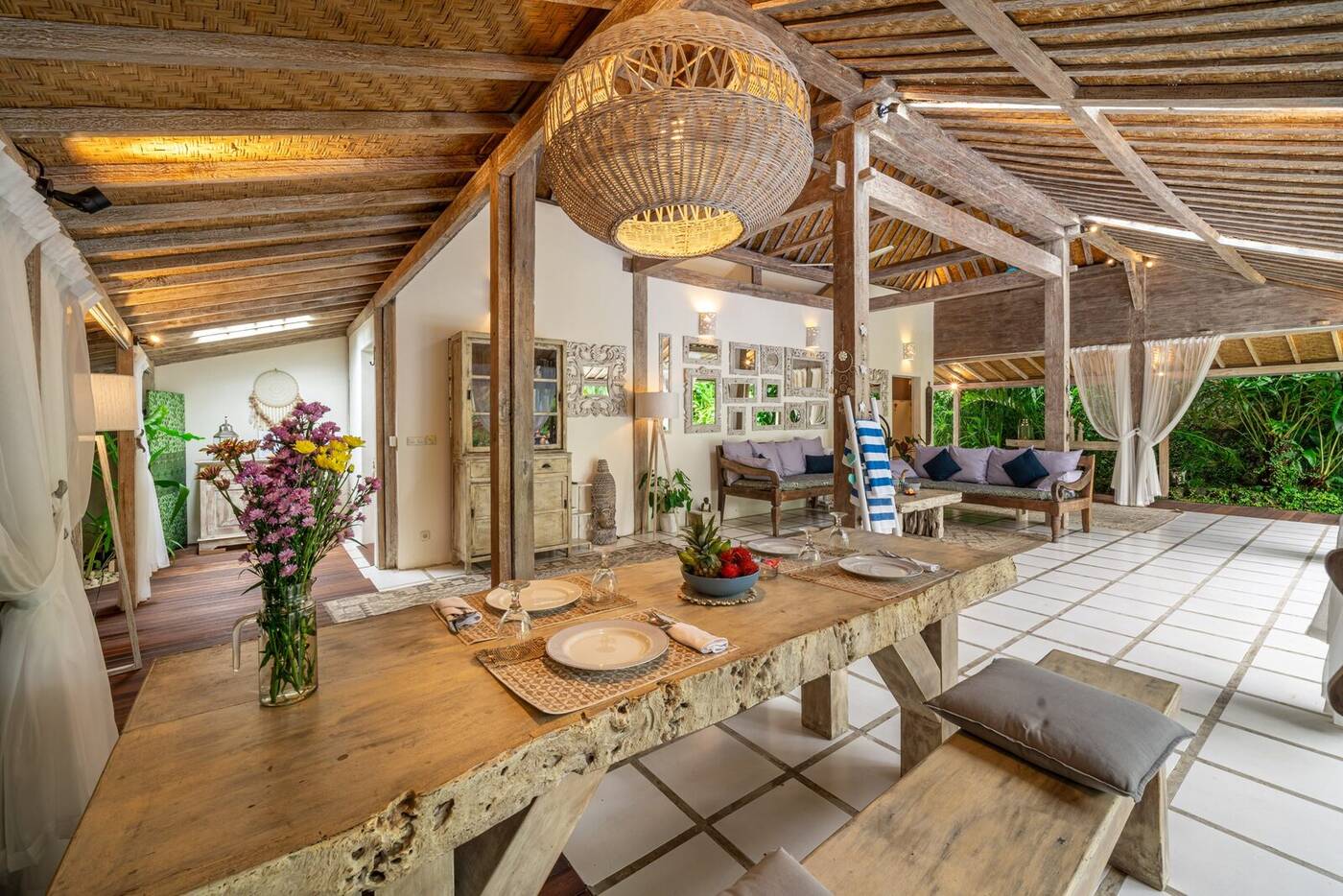 Long wooden dining table under rattan lamp, Canggu villa, Bali