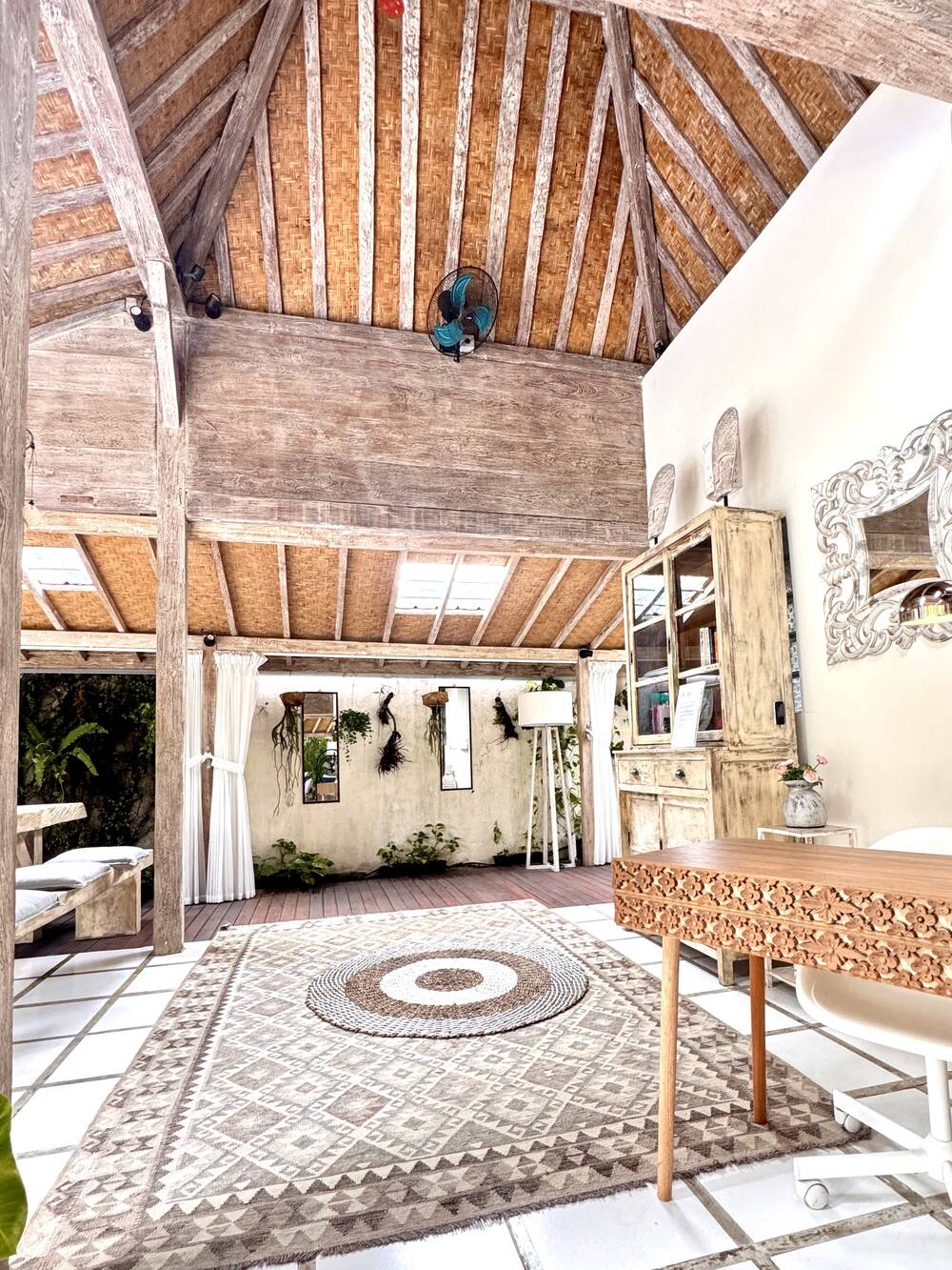 Workspace with carved wooden desk and ergonomic chair in the open Joglo living area, Villa Desa Naga 1, Canggu, Bali
