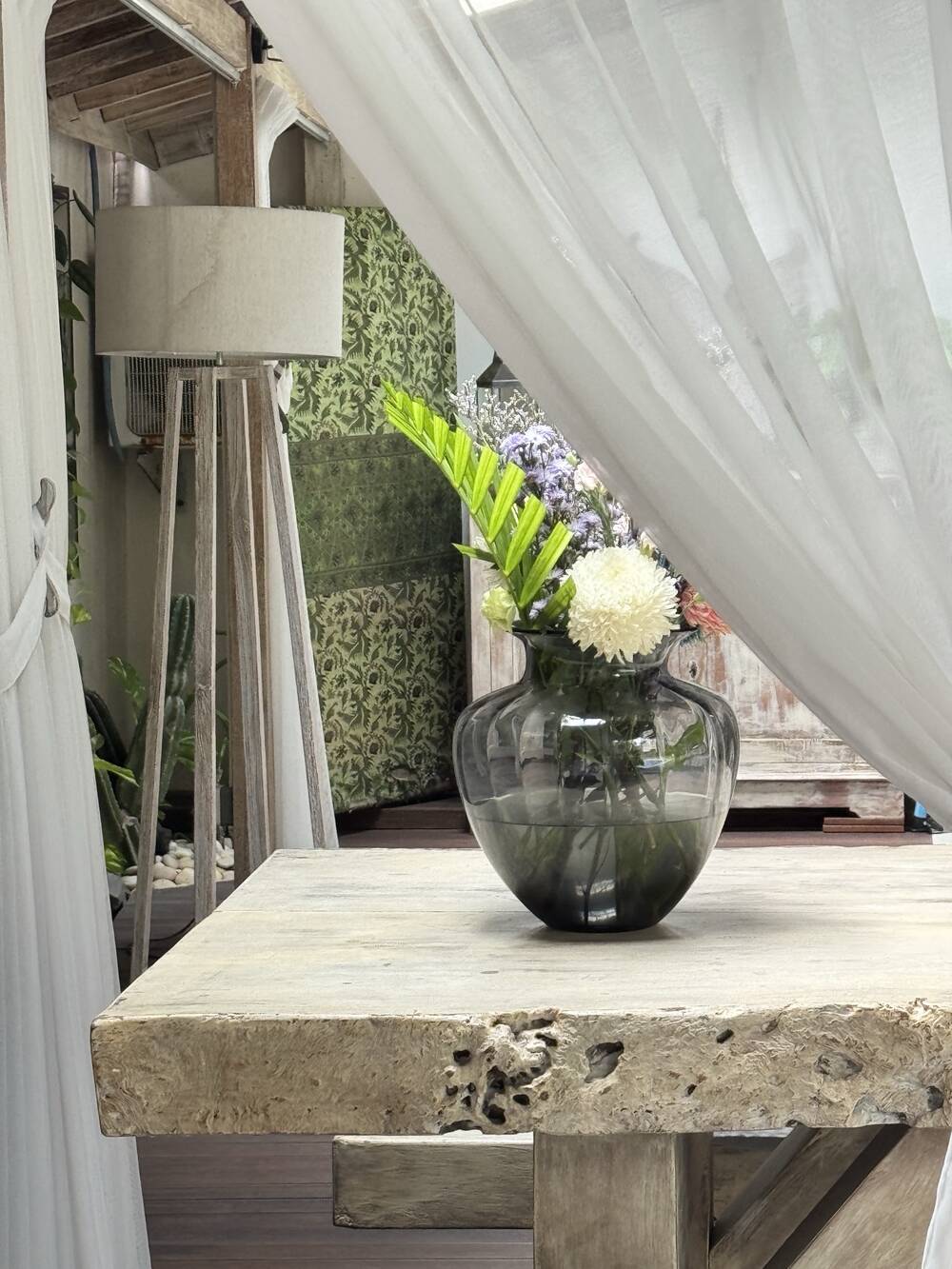 Fresh flowers on a teak table with white curtains, Canggu villa, Bali